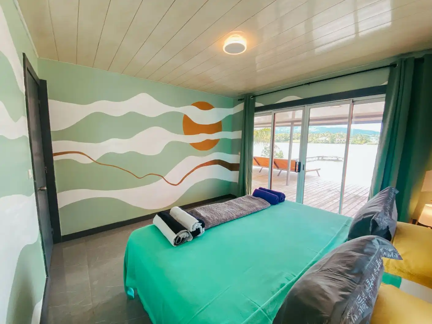 A luxurious bedroom at Villa Mahana with a large window offering a stunning view of the lagoon at Villa Mitirapa.